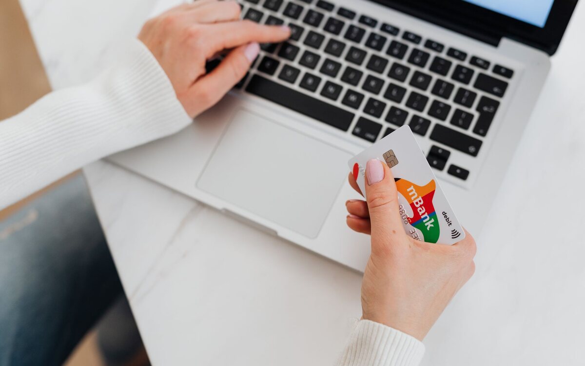 Pessoa pagando pela internet com o cartão na mão