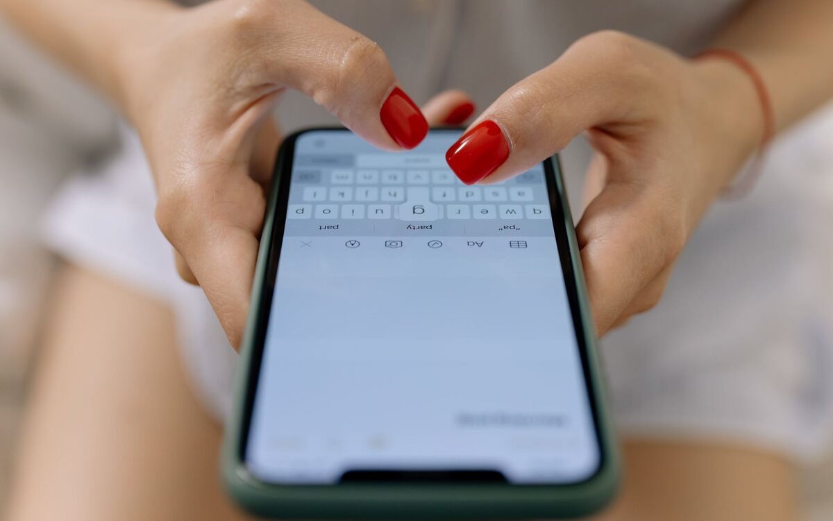 Mãos digitando uma mensagem no celular